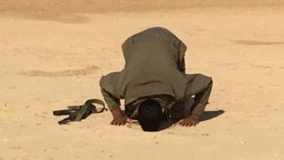 Shia fighter prays during a break in an assault on IS targets in mainly Sunni villages