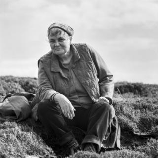 A woman sits on a rock