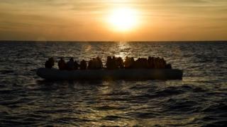 Migrants and refugees sit on a rubber boat in a boat off the coast of Libya - 5 November 2016