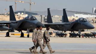 Oficiales sauditas caminan junto a cazas F-15 en una base aÃ©rea en Riad.