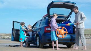 A family unpacking a car on a beach