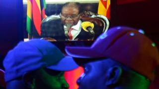 People watch as Zimbabwean President Robert Mugabe addresses the nation on television, at a bar in Harare, Zimbabwe, 19 November 2017