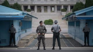 South Korean soldiers stand guard before North Korea's Panmon Hall (rear C) and the military demarcation line separating North and South Korea, at Panmunjom, on 6 August