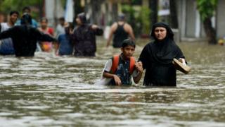 Una mujer camina con su hijo por una calle inundada en Mumbai.