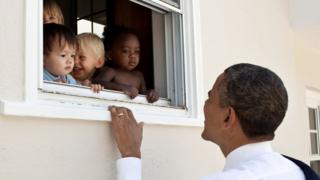 El expresidente de EE.UU., Barack Obama, sonríe a un grupo de niños en una guardería.