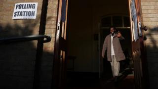 A man waves as he leaves a polling station as voting begins in local government elections in London, Britain