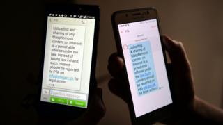 Pakistani cellphone users reads a text message circulated by the Pakistan Telecommunication Authority (PTA) on their mobile devices in Islamabad on May 10, 2017. Pakistan's telecom regulator has circulated a warning via text messages reminding people that sharing blasphemous content was an offence and asked them to report such content, a step criticised by rights activists. / AFP PHOTO / AAMIR QURESHI (Photo credit should read AAMIR QURESHI/AFP/Getty Images)