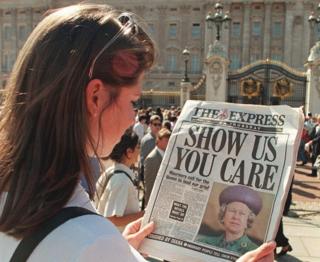 Una mujer lee un periódico con el titular "Show us you care" (Demuéstranos que te importa)