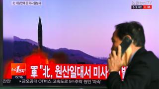 Man in Seoul walks past a TV screen showing file footage of North Korean missile launch on March 22, 2017