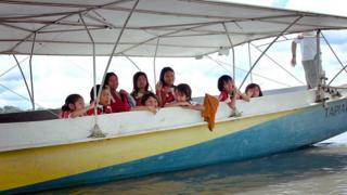 Children on the solar canoe on their way to school