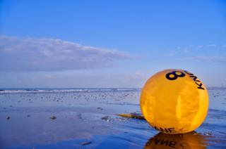 A buoy on a beach at sunrise