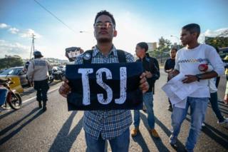 Joven con un cartel que dice TSJ protesta en Caracas, Venezuela.