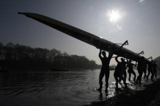 Oxford University men's boat crew carry their boat out of the water following training on the River Thames ahead of this year's Oxford v Cambridge Boat Race in London on Sunday