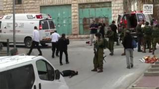 A scene from the video showing a soldier raising his gun at the wounded Palestinian