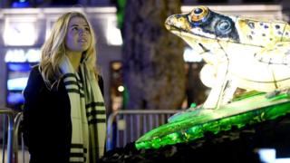 Woman looks at lit-up frog as part of Lumiere Festival