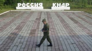 A guard walks along a platform past signs, which read "Russia" (L) and "DPRK"(Democratic People"s Republic of Korea), at the border crossing between Russia and North Korea in the settlement of Tumangan, North Korea July 18, 2014