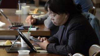 北京某咖啡店内顾客用智能手机和平板电脑上网(资料图片)