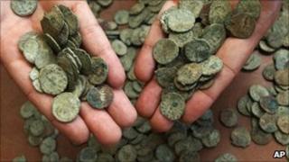 British Museum staff member displays a handful of the coins
