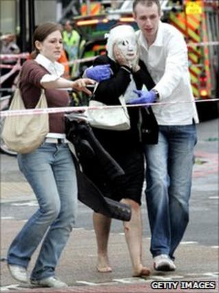 Davinia, her face covered in with a gauze mask, is helped by Paul Dadge and another volunteer who carries Davinia's shoes and jacket