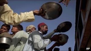 Pakistani men line up to receive a fresh meal at a camp for families displaced by floods run by the Pakistan Air Force in Sukkur, Sindh province