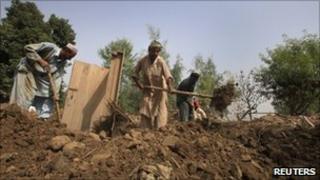 Residents remove debris from their destroyed home in NW Pakistan