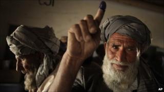 An elderly Pashtun man holds up his ink-stained finger as he votes in the parliamentary elections in Kabul