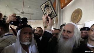 Rabbi Menachem Froman holds up a Koran at the fire-damaged mosque in Beit Fajjar (5 October 2010)