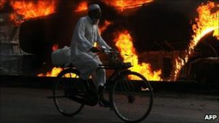 Cyclist passes burning Nato supply tanker