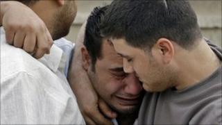 An Iraqi man is consoled by friends at a Catholic church in Baghdad, where dozens died on Sunday after gunmen attempted to take worshippers hostage