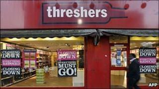 Man walks past a Threshers store