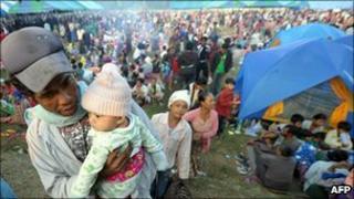 A man carries his child as Burmese refugees arrive in a temporary camp set up at a police base on the border town of Mae Sot
