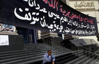 An Egyptian journalist sits under a slogan supporting Ibrahim Issa outside the Syndicate of Journalists in Cairo (18 October 2010)