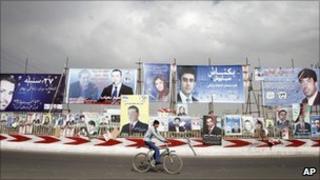 An Afghan youth rides his bicycle past election posters in Kabul on 5 September 2010