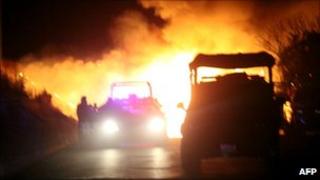 Mexican federal police officers stand by a burning blockade set up by drug cartel gunmen in the western state of Michoacan