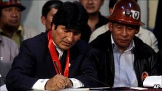 Evo Morales (left) signing the pensions law beside a trade union leader
