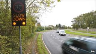 Speed limit warning sign with car approaching
