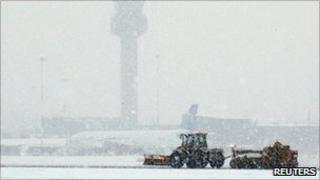 Snow ploughs clear a runway