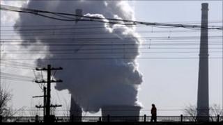 A chimney billows smoke from a coal-burning power station behind powerlines and railway tracks in Beijing