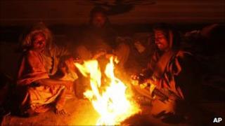 People huddle around a fire during a cold snap in India