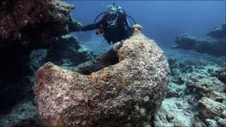 A maritime archaeologist examines a try pot from the Two Brothers.