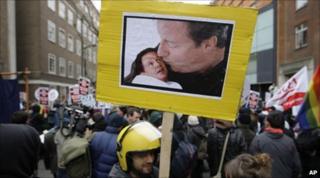 A student fees protestor holds a placard showing a manipulated photo of David Cameron kissing a baby Nick Clegg.