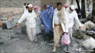 A victim is carried out of an arms factory in Yemen, 28 March 2011