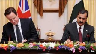 David Cameron signs a document with Pakistan PM Yousuf Raza Gilani