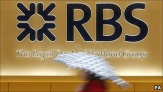 Woman walks past an RBS sign