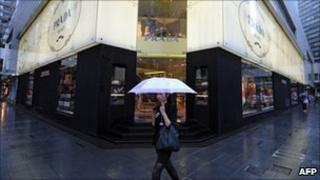 A woman walk past a Prada store in Hong Kong