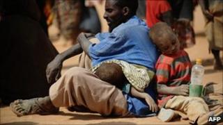 A Somali man who fled violence and drought in Somalia with his family sits on the ground outside a food distribution point in the Dadaab refugee camp in north-eastern Kenya on 5 July 2011