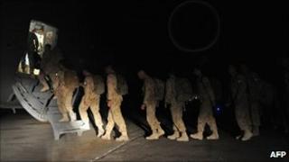 Canadian soldiers walk to board a plane on their way home at Kandahar airbase on July 5, 2011