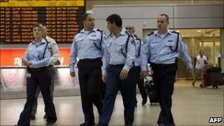 Israeli police walk past airport arrivals board.