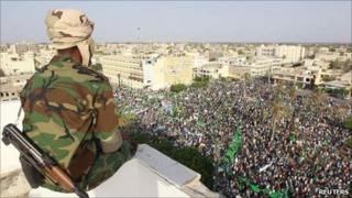 A Libyan soldier watches as supporters of Libya's leader Muammar Gaddafi take part in a rally in the town of Zawiya, 16 July 2011 - photo taken on government guided tour