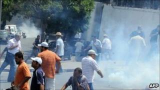 Demonstrators and a cameraman run for cover after tear gas was used by Tunisian security forces to disperse them in La Kasbah square, on July 15, 2011.